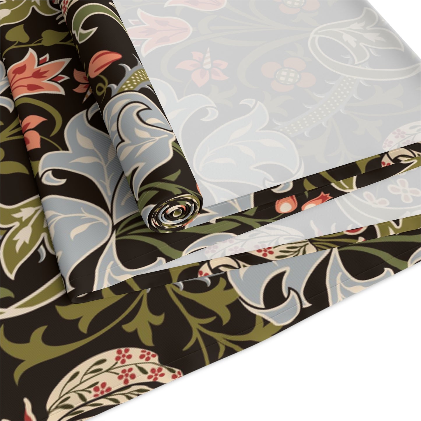 A table runner with a floral William Morris & Co pattern in shades of green, gold, and other colours, laid out on a dining table with dishes and glasses arranged on top.