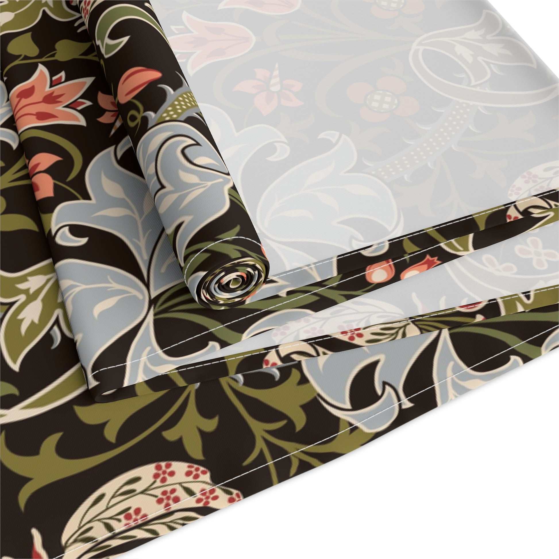 A table runner with a floral William Morris & Co pattern in shades of green, gold, and other colours, laid out on a dining table with dishes and glasses arranged on top.