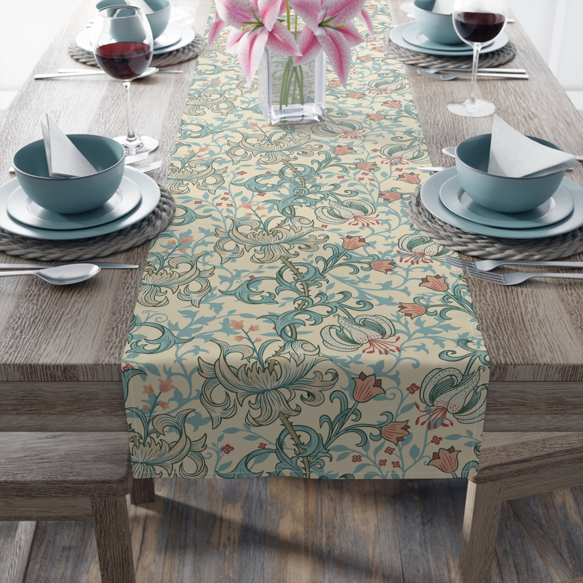 A table runner with a floral William Morris & Co pattern in green, beige, and gold colours, laid out on a dining table.
