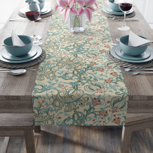 A table runner with a floral William Morris & Co pattern in green, beige, and gold colours, laid out on a dining table.