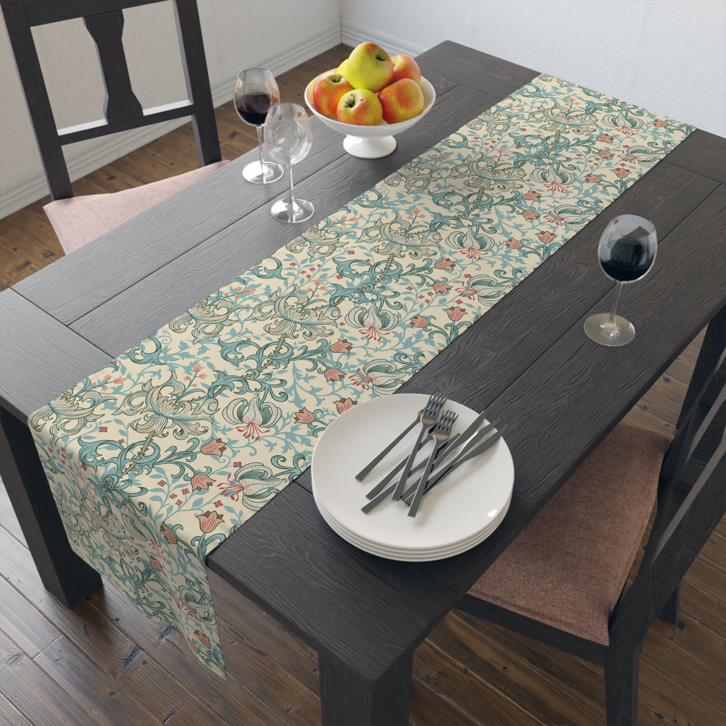 A table runner with a floral William Morris & Co pattern in green, beige, and gold colours, laid out on a dining table.