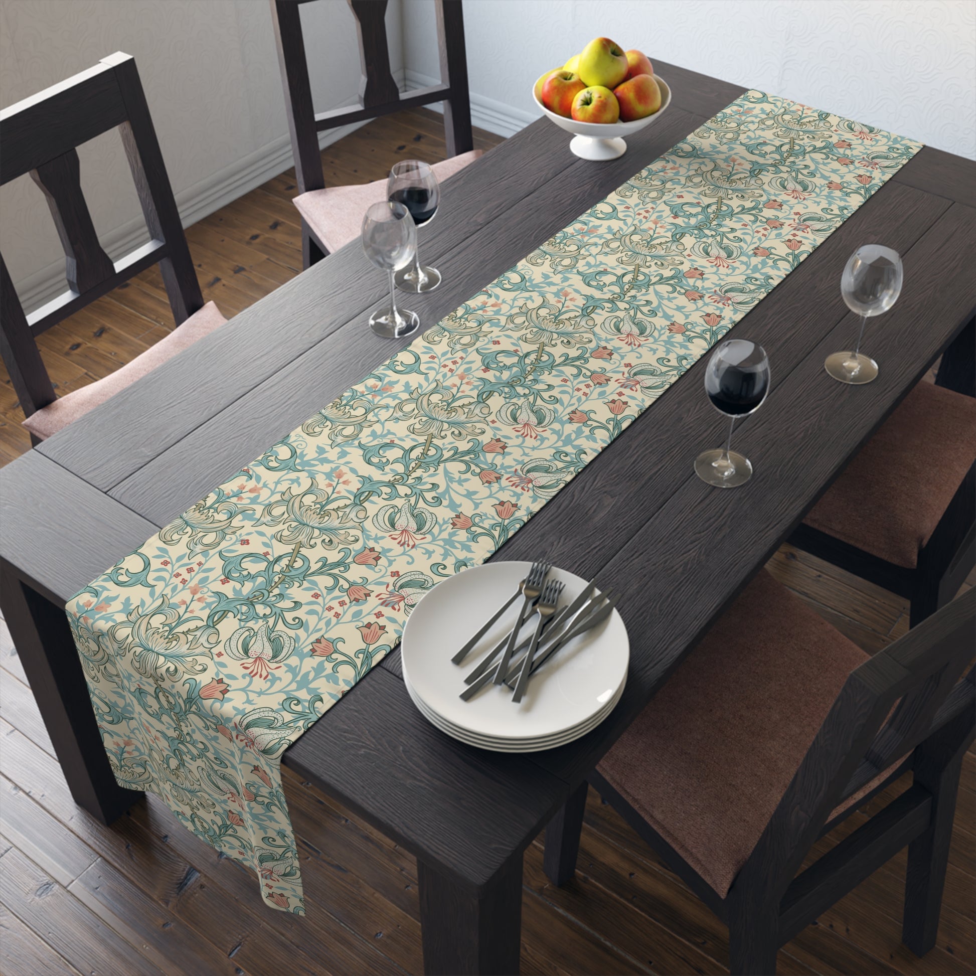 A table runner with a floral William Morris & Co pattern in green, beige, and gold colours, laid out on a dining table.
