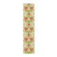 A table runner with a floral William Morris & Co pattern in red, green, and white colours, laid out on a dining table.