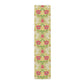 A table runner with a floral William Morris & Co pattern in red, green, and white colours, laid out on a dining table.