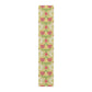 A table runner with a floral William Morris & Co pattern in red, green, and white colours, laid out on a dining table.