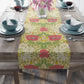 A table runner with a floral pattern in red, green, and white colors, laid out on a dining table.