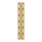A table runner with a floral William Morris & Co pattern in red, green, and white colours, laid out on a dining table.