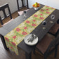 A table runner with a floral William Morris & Co pattern in red, green, and white colours, laid out on a dining table.
