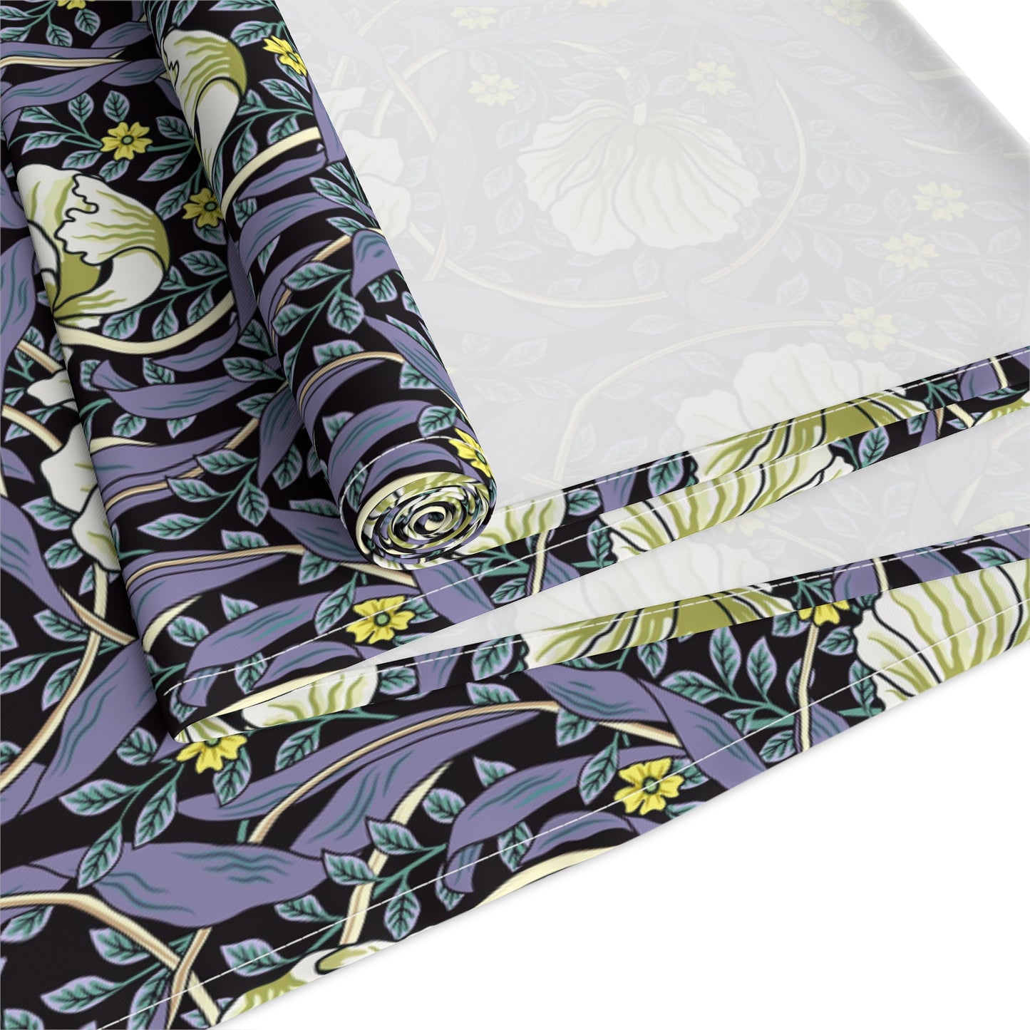 A table runner with a floral William Morris & Co pattern in shades of purple and green laid out on a dining table.