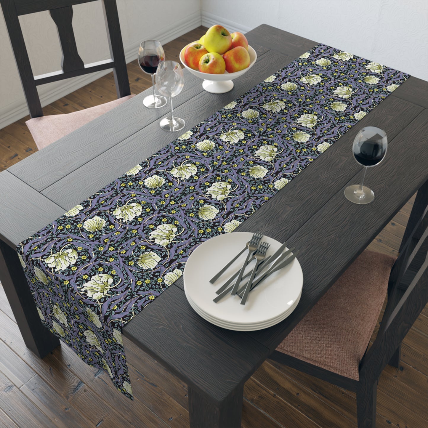A table runner with a floral William Morris & Co pattern in shades of purple and green laid out on a dining table.