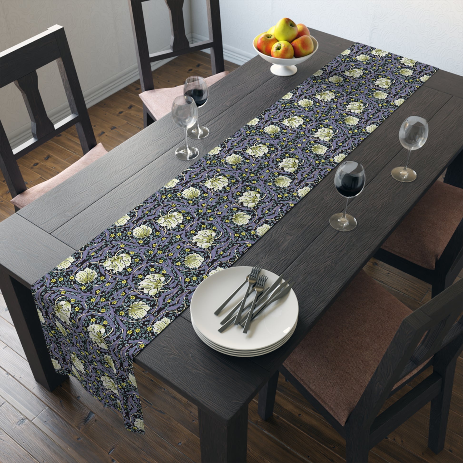 A table runner with a floral William Morris & Co pattern in shades of purple and green laid out on a dining table.