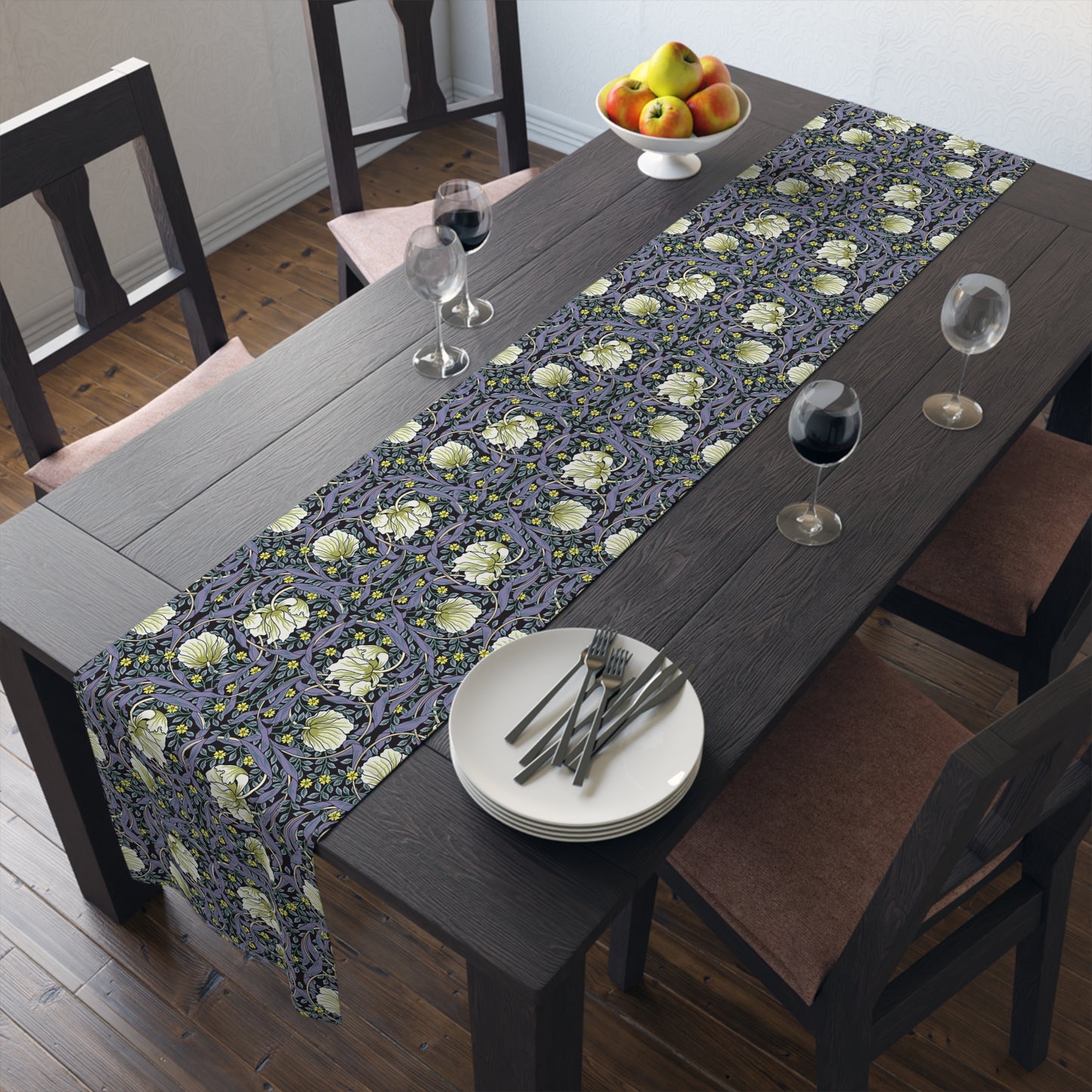 A table runner with a floral William Morris & Co pattern in shades of purple and green laid out on a dining table.