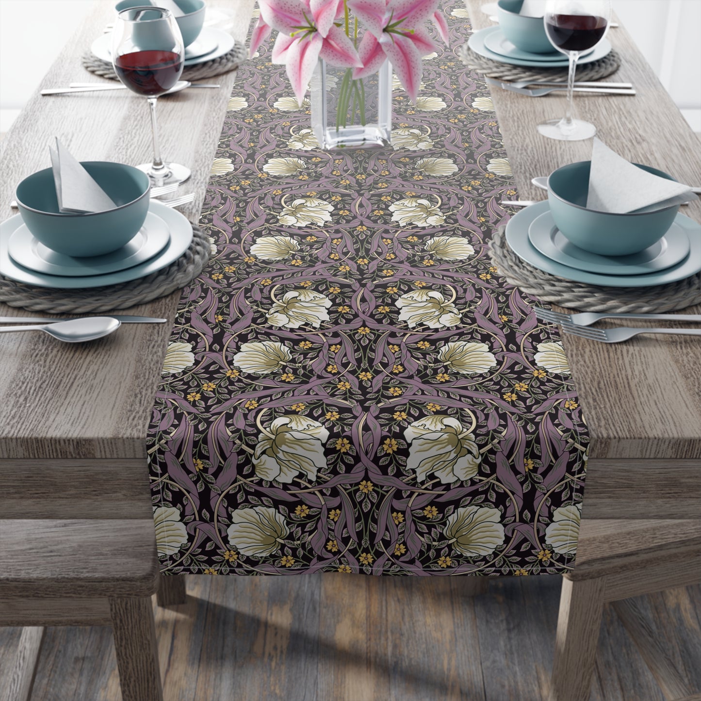 A table runner with a floral William Morris & Co pattern in purple, gold, and green colours, laid out on a dining table.