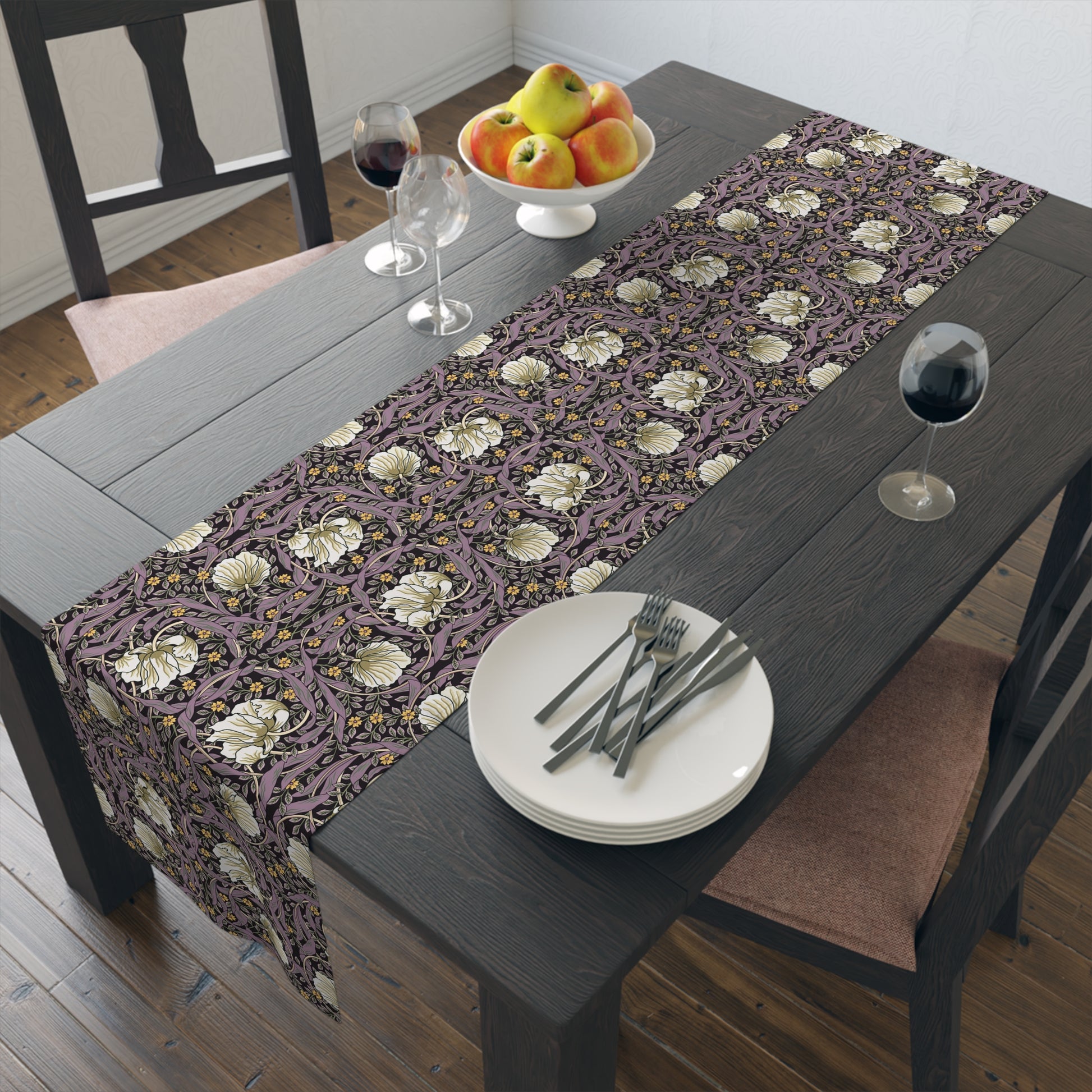 A table runner with a floral William Morris & Co pattern in purple, gold, and green colours, laid out on a dining table.