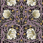 A table runner with a floral William Morris & Co pattern in purple, gold, and green colours, laid out on a dining table.