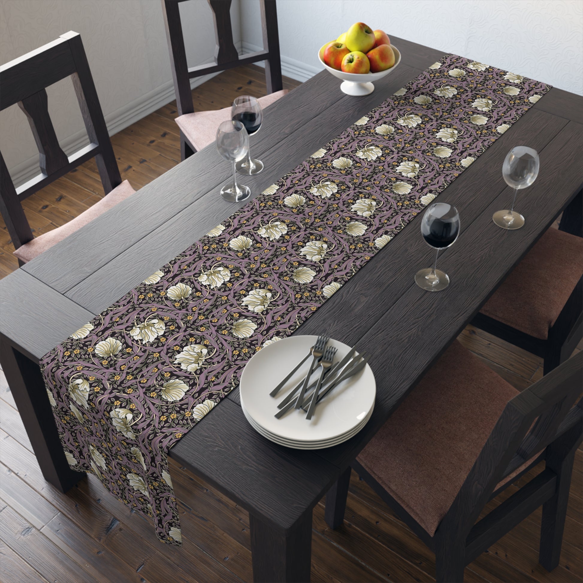 A table runner with a floral William Morris & Co pattern in purple, gold, and green colours, laid out on a dining table.