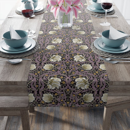 A table runner with a floral pattern in purple, gold, and green colors, laid out on a dining table.