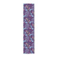 A multicolored table runner with a floral William Morris & Co pattern in pink and green on a blue background, displayed on a table with dishes and cutlery.