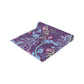 A multicolored table runner with a floral William Morris & Co pattern in pink and green on a blue background, displayed on a table with dishes and cutlery.