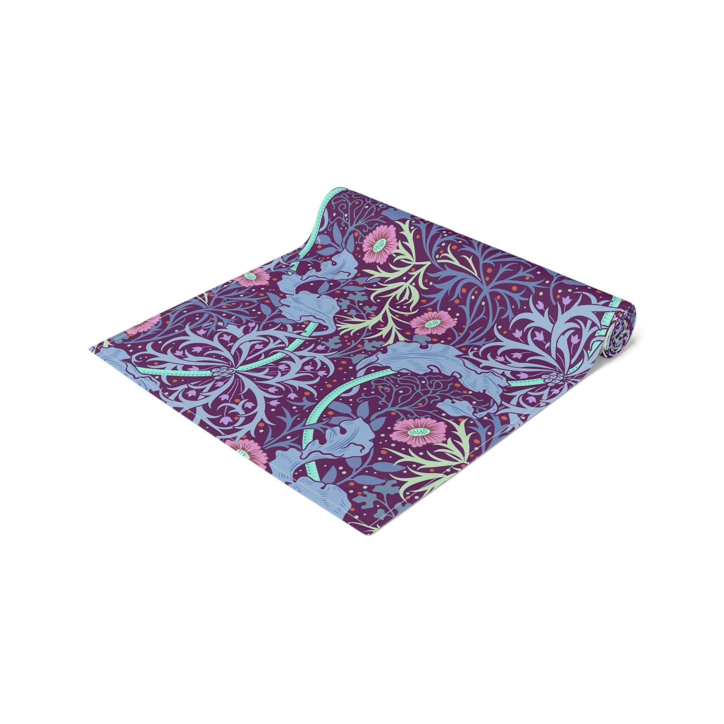 A multicolored table runner with a floral William Morris & Co pattern in pink and green on a blue background, displayed on a table with dishes and cutlery.