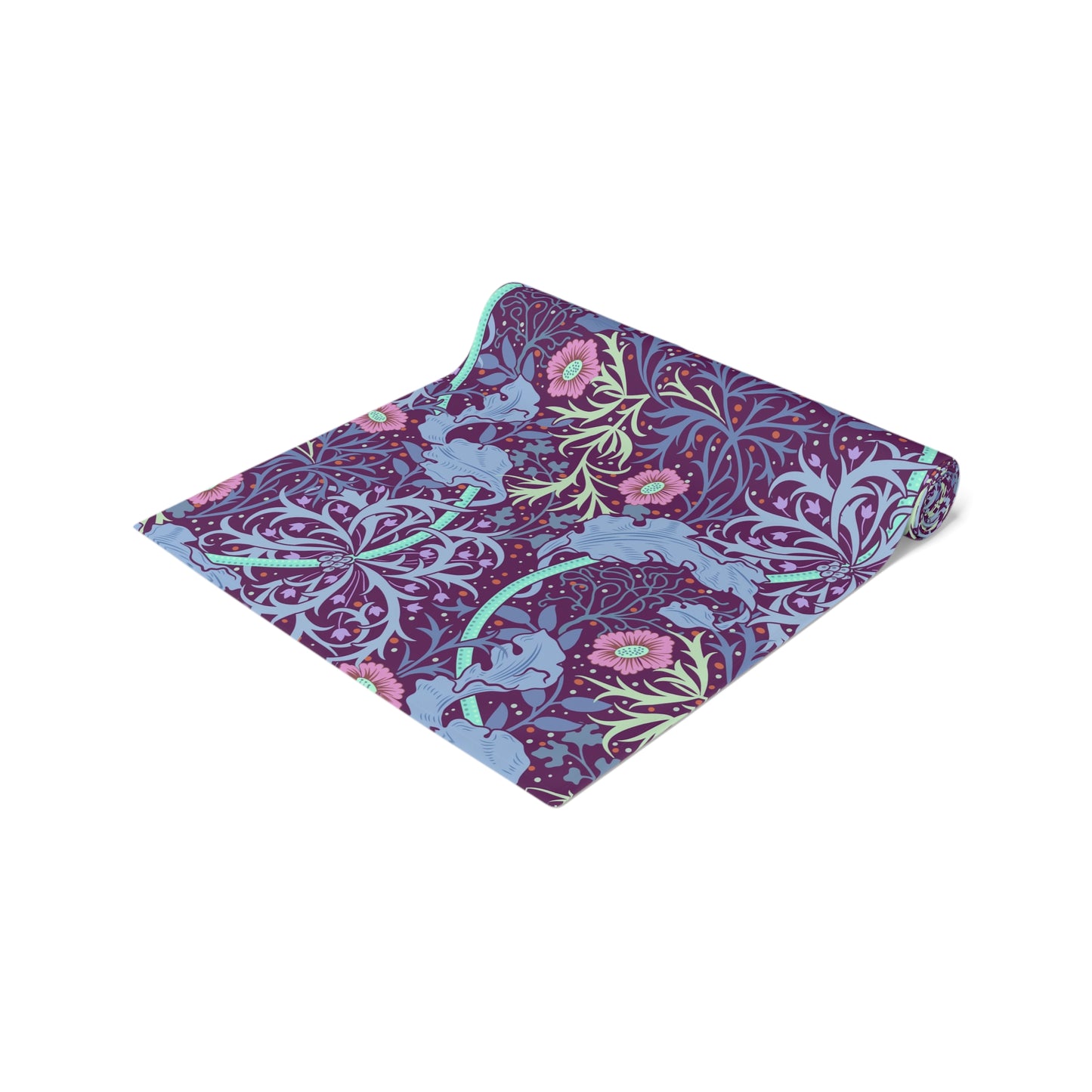 A multicolored table runner with a floral William Morris & Co pattern in pink and green on a blue background, displayed on a table with dishes and cutlery.