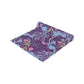 A multicolored table runner with a floral William Morris & Co pattern in pink and green on a blue background, displayed on a table with dishes and cutlery.