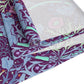 A multicolored table runner with a floral William Morris & Co pattern in pink and green on a blue background, displayed on a table with dishes and cutlery.