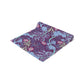 A multicolored table runner with a floral William Morris & Co pattern in pink and green on a blue background, displayed on a table with dishes and cutlery.