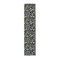 A table runner with a floral William Morris & Co pattern in yellow and green shades displayed on a dining table.