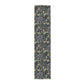 A table runner with a floral William Morris & Co pattern in yellow and green shades displayed on a dining table.