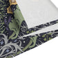 A table runner with a floral William Morris & Co pattern in yellow and green shades displayed on a dining table.