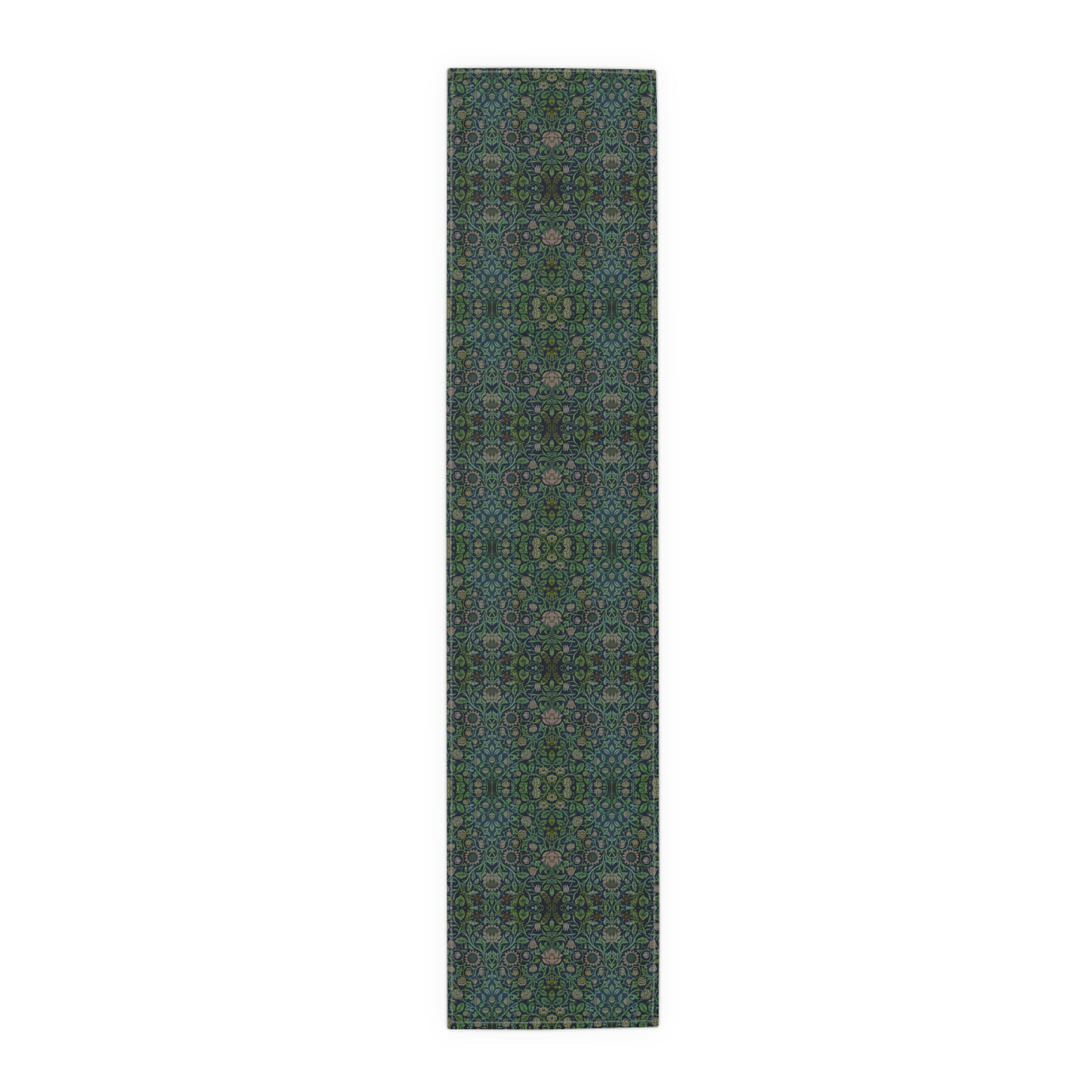 A green floral patterned table runner inspired by William Morris, laid out on a wooden dining table with plates and cutlery set on top.