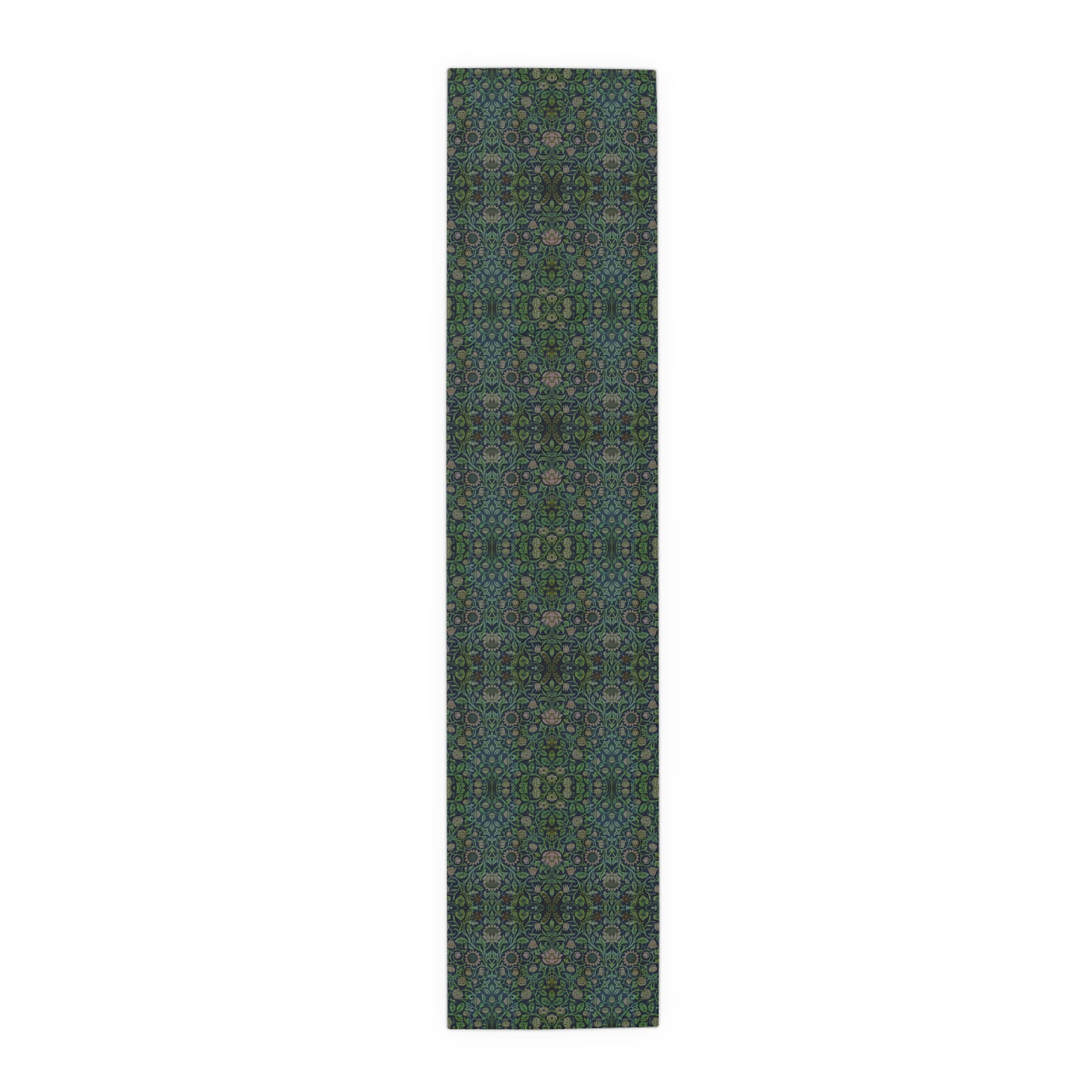 A green floral patterned table runner inspired by William Morris, laid out on a wooden dining table with plates and cutlery set on top.