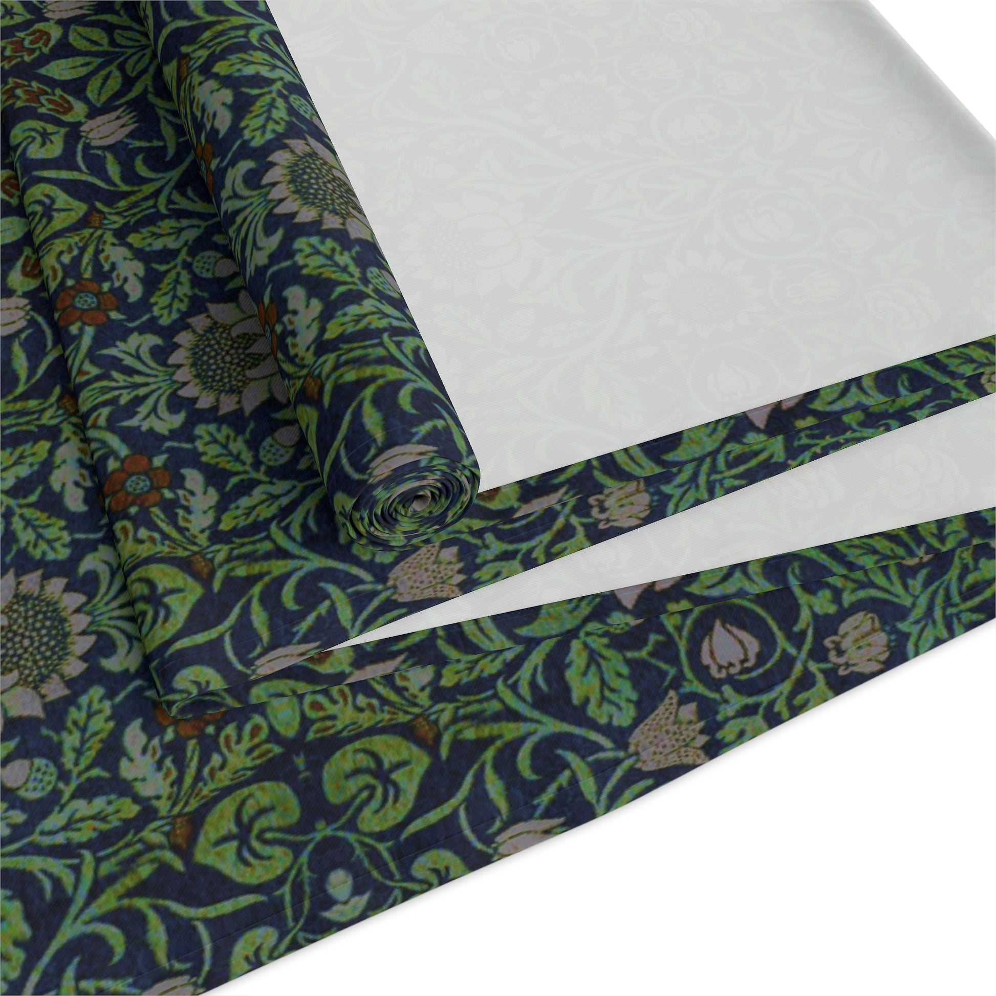 A green floral patterned table runner inspired by William Morris, laid out on a wooden dining table with plates and cutlery set on top.