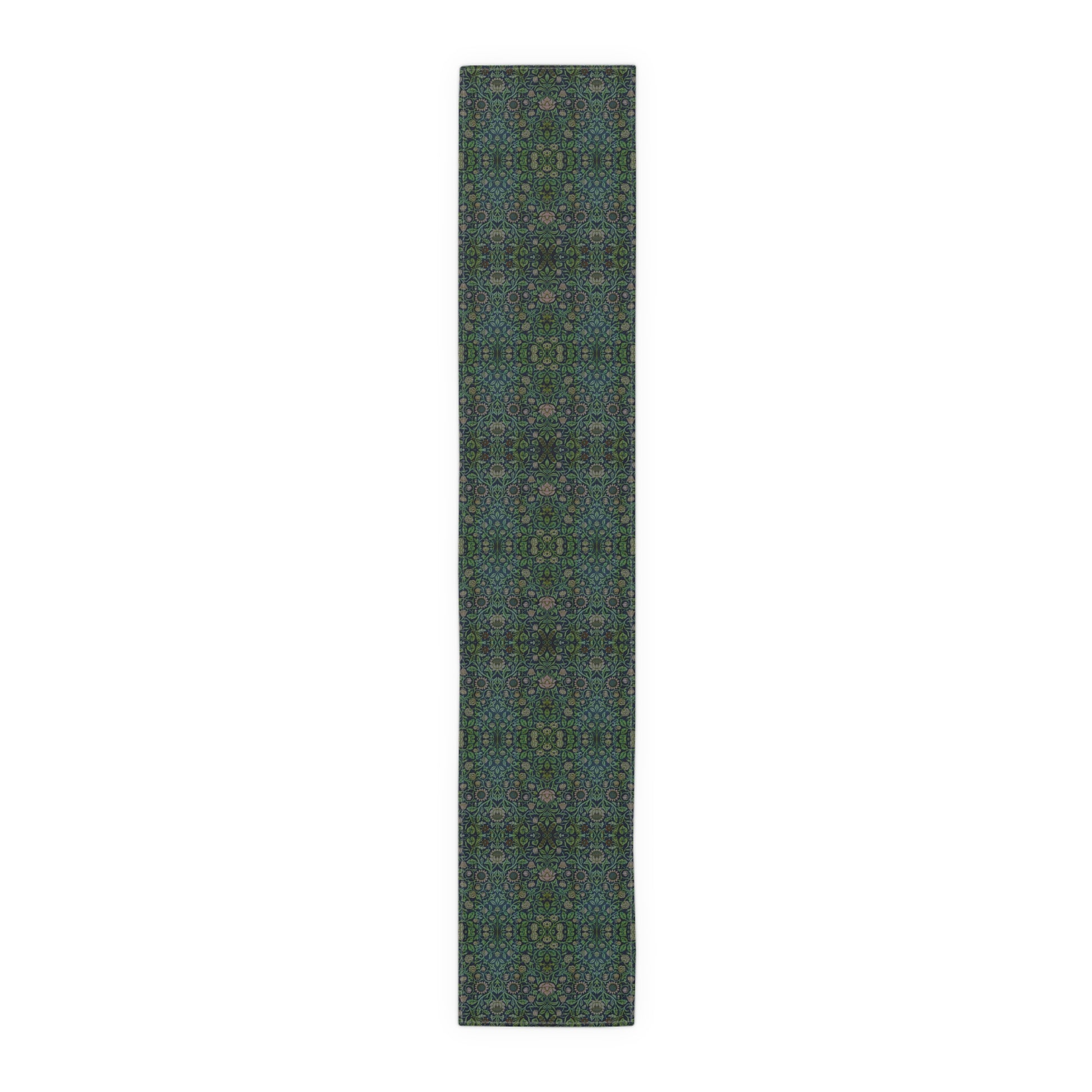 A green floral patterned table runner inspired by William Morris, laid out on a wooden dining table with plates and cutlery set on top.