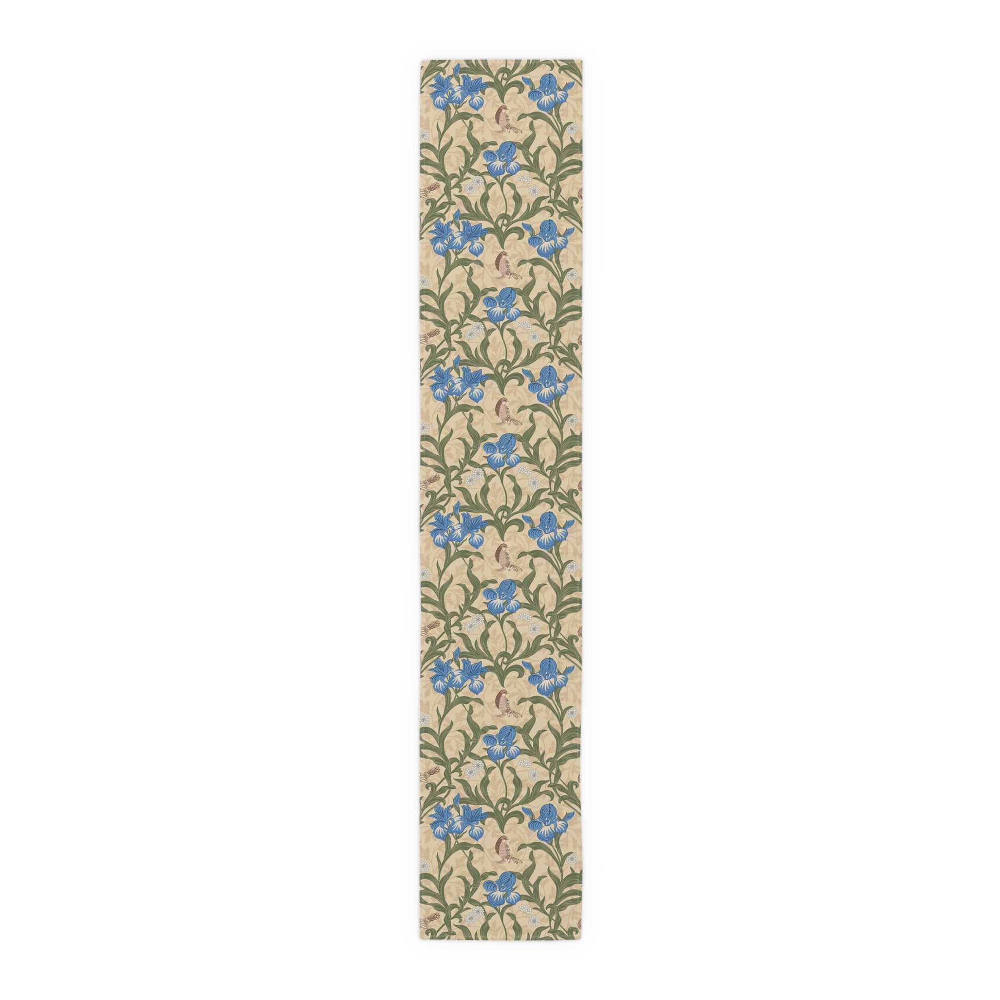 A table runner with a Victorian floral design in blue and green on a beige background, laid out on a dining table with place settings and decorative flowers.