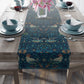 A William Morris & Co table runner with a bluebird design laid out on a dining table, featuring a repeating pattern with birds and foliage.