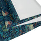 A William Morris & Co table runner with a bluebird design laid out on a dining table, featuring a repeating pattern with birds and foliage.