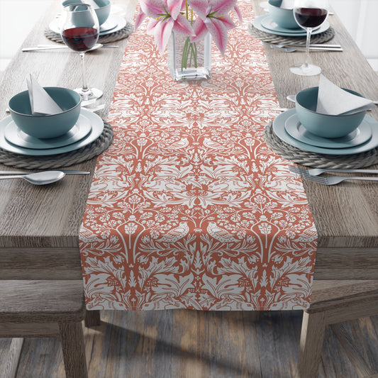 Dining table set with a patterned table runner, blue bowls, and pink flowers.