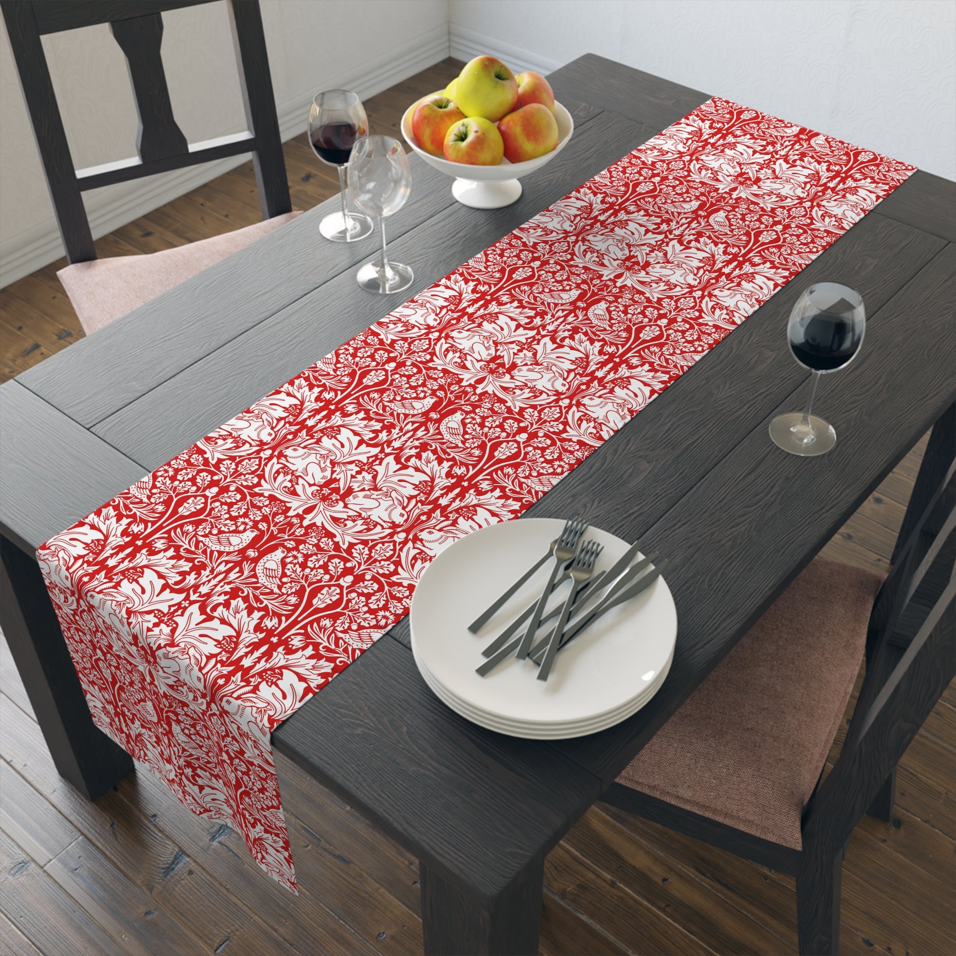 Dining table with a red and white floral table runner, plates, and glasses.