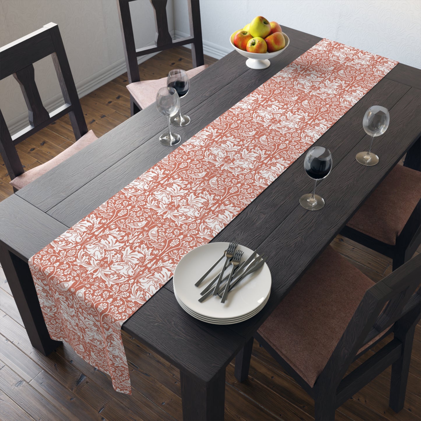 Dining table with a floral table runner, plates, and glasses in a room.