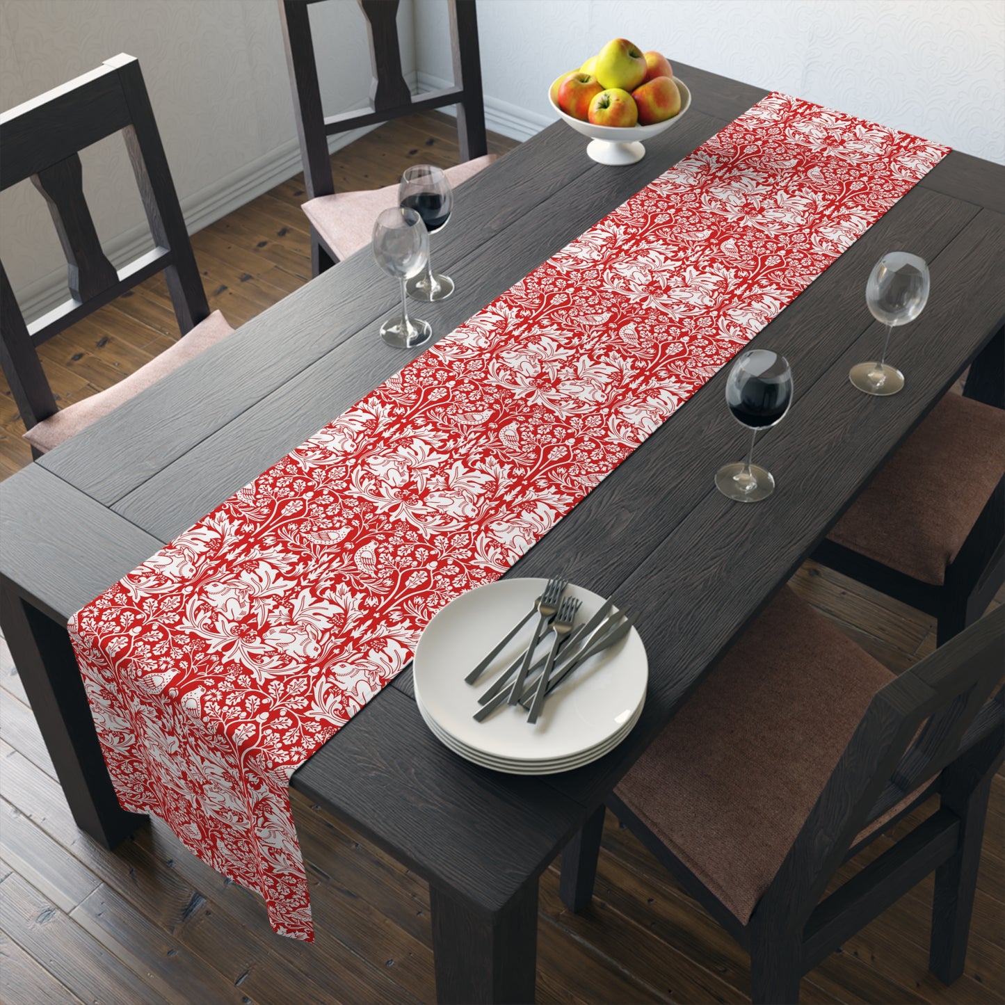 Dining table with a red and white floral table runner, plates, and glasses.
