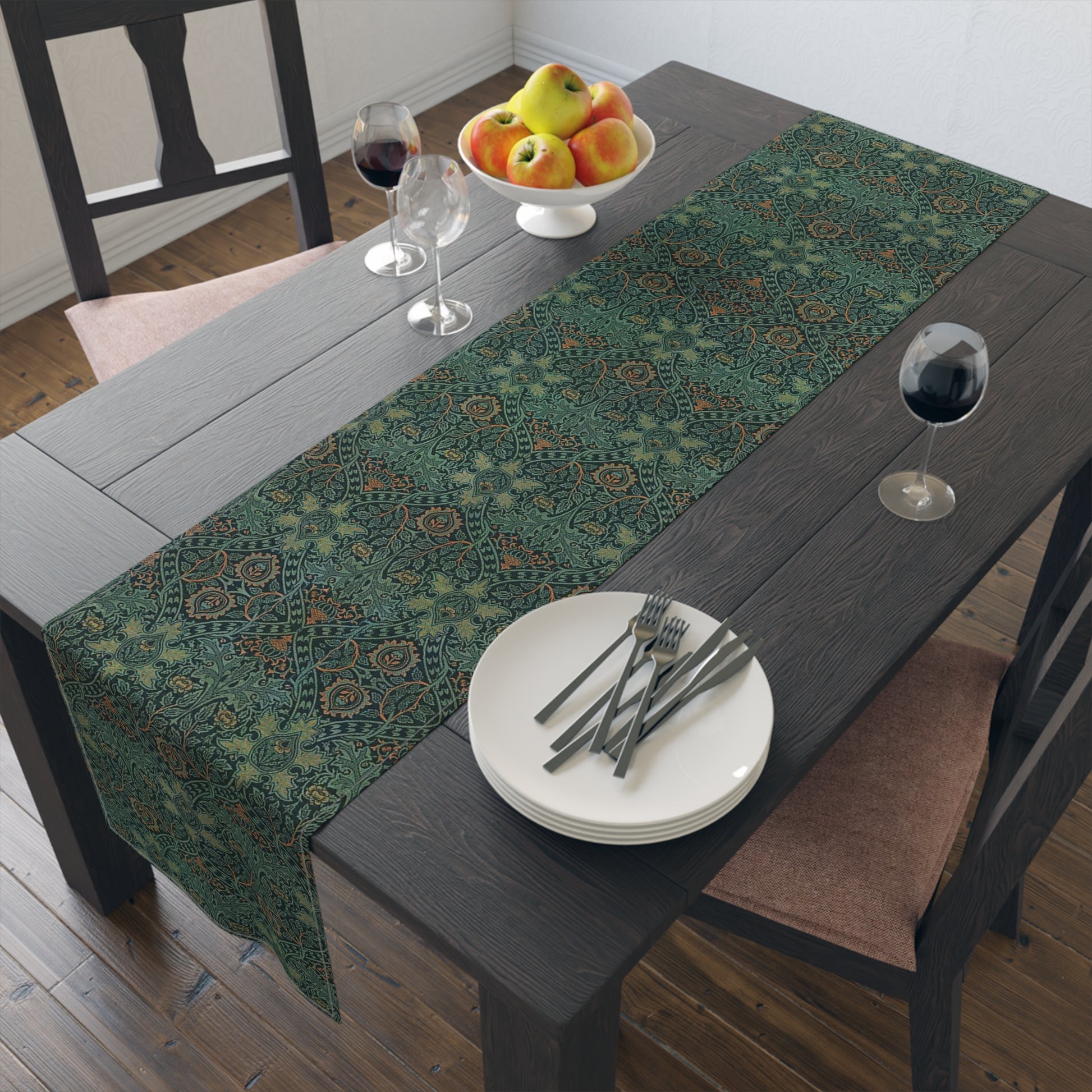 A green table runner with a floral pattern inspired by William Morris, displayed on a dining table with dishes and cutlery.