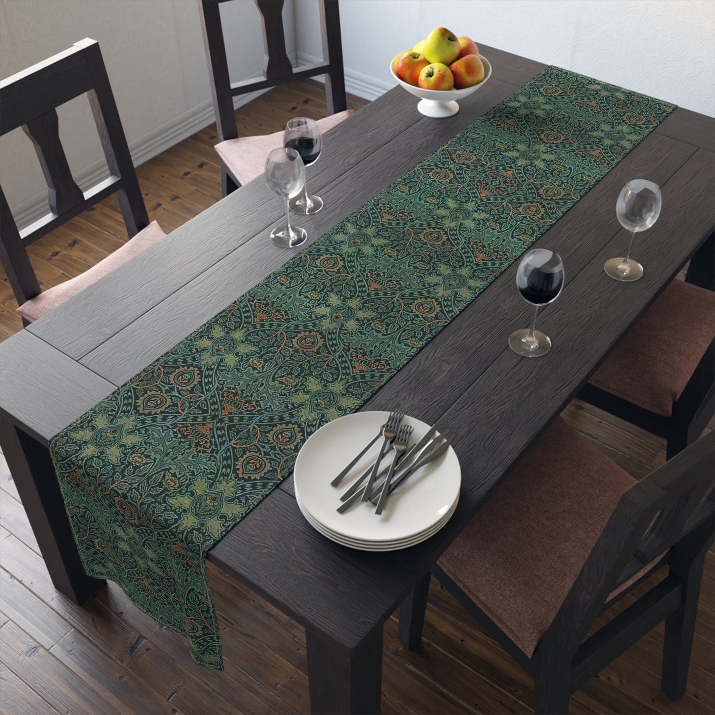 A green table runner with a floral pattern inspired by William Morris, displayed on a dining table with dishes and cutlery.