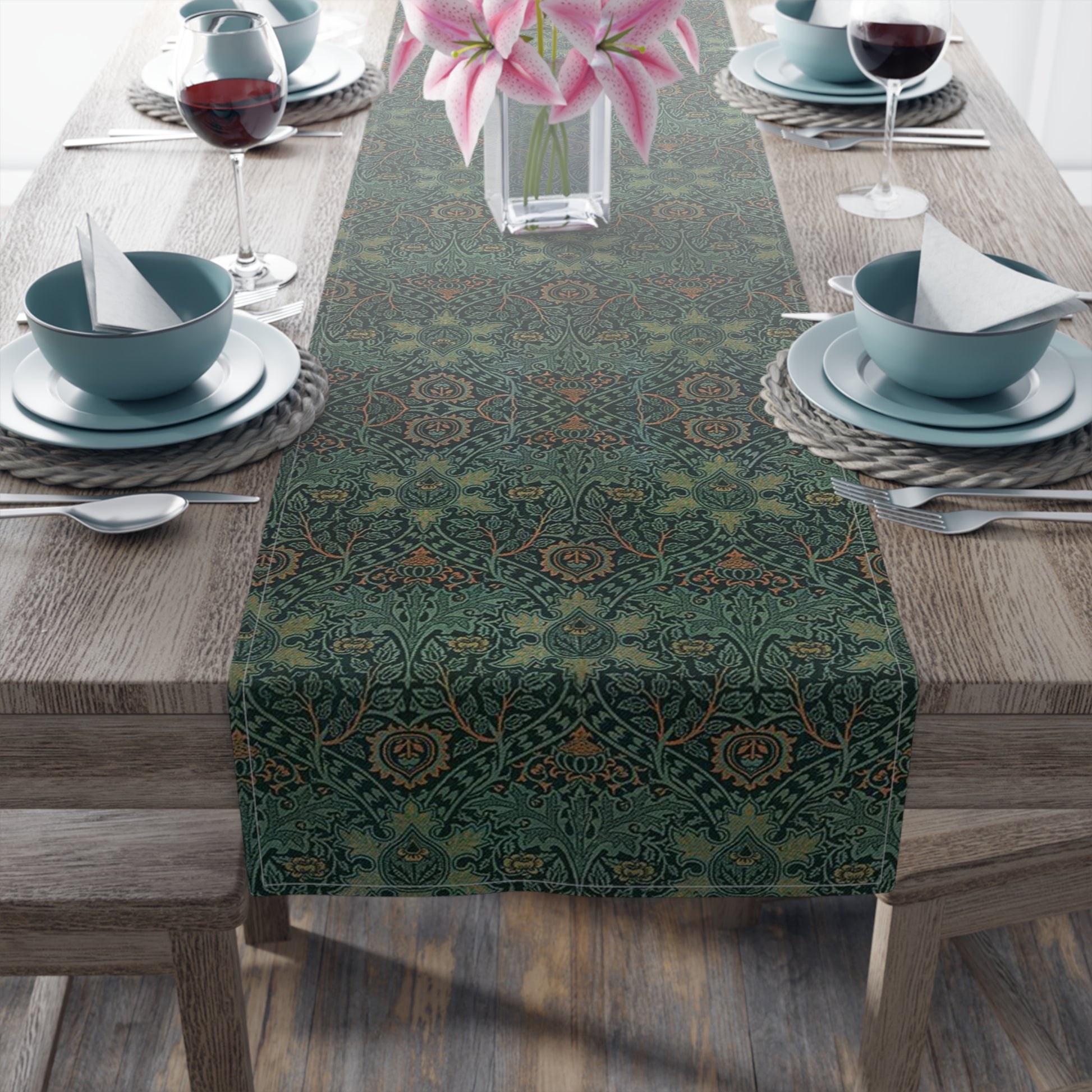 A green table runner with a floral pattern inspired by William Morris, displayed on a dining table with dishes and cutlery.