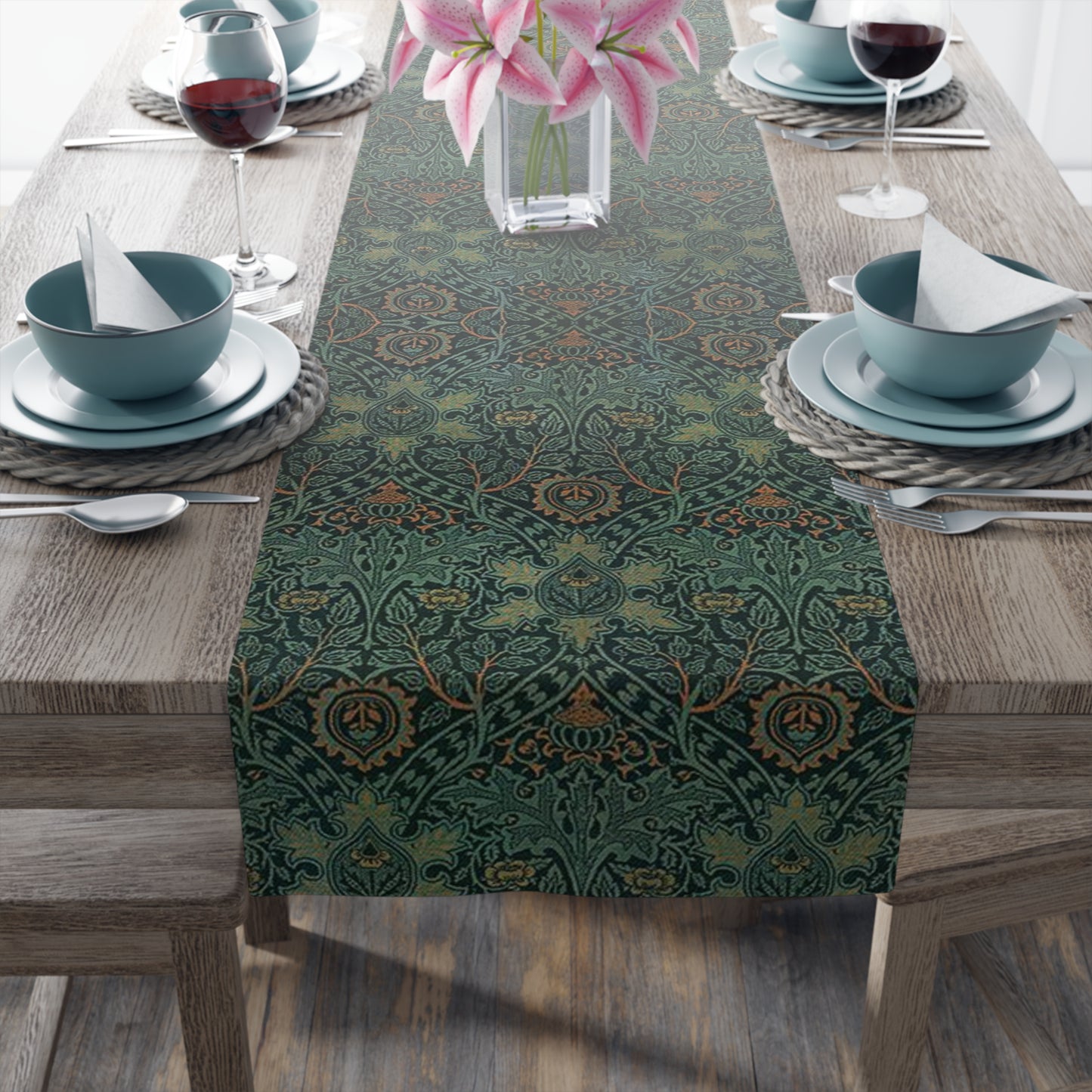 A green table runner with a floral pattern inspired by William Morris, displayed on a dining table with dishes and cutlery.