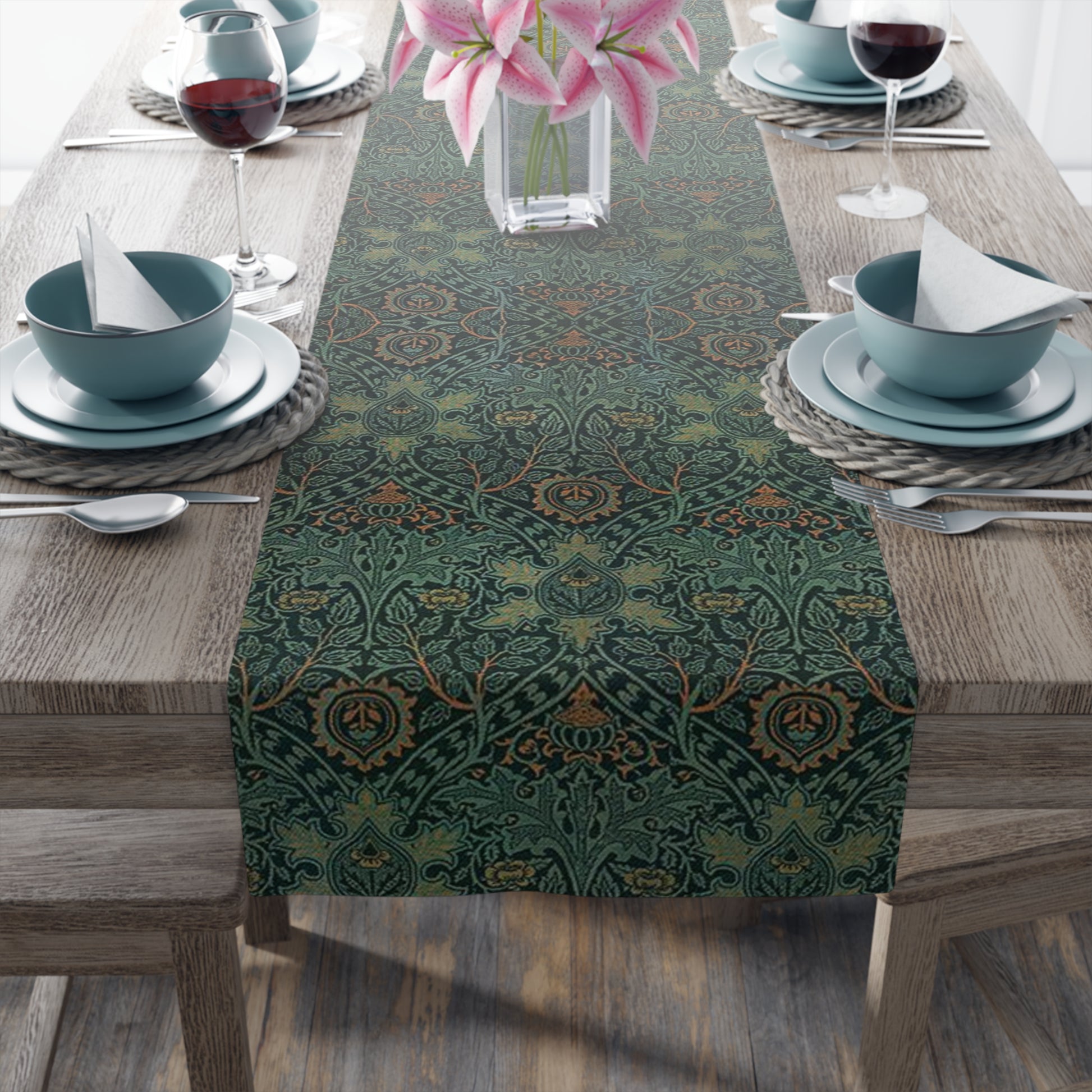 A green table runner with a floral pattern inspired by William Morris, displayed on a dining table with dishes and cutlery.