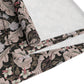 A table runner with a William Morris & Co design laid out on a dining table, flanked by plates and a vase with flowers, set for a meal.