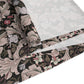 A table runner with a William Morris & Co design laid out on a dining table, flanked by plates and a vase with flowers, set for a meal.