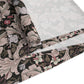 A table runner with a William Morris & Co design laid out on a dining table, flanked by plates and a vase with flowers, set for a meal.